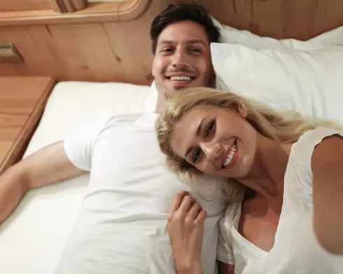 Paar macht ein Selfie in einem Doppelbett