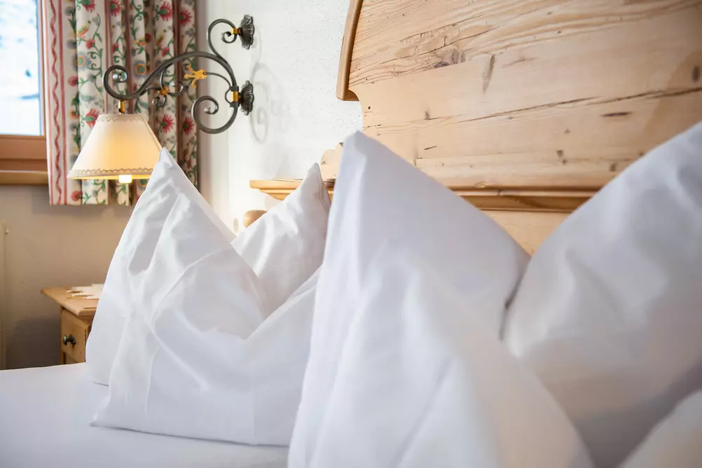 Weiße Kopfpolster auf einem Bett mit hölzernem Kopfteil