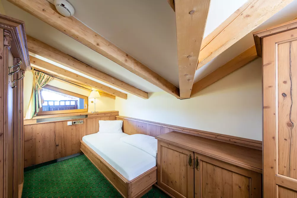 Hotelzimmer mit Einzelbett, Dachschräge und Holzmöbeln