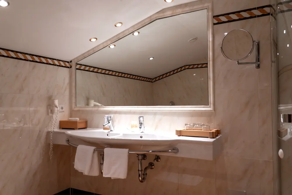 Modernes Badezimmer mit Doppelwaschbecken, großem Spiegel und hellen Fliesen