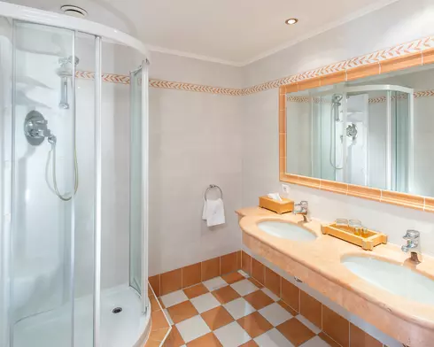 Bad mit geräumiger Dusche, großem Wandspiegel und Doppelwaschbecken