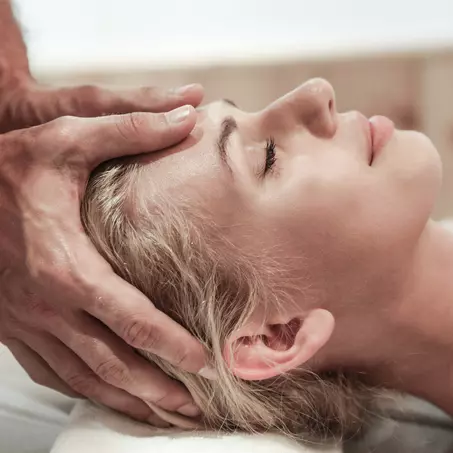 Frau bei einer Kopfmassage auf einem Massagetisch