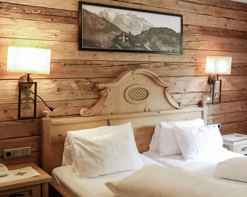 Doppelbett aus Holz in einem Hotelzimmer mit holzvertäfelter Wand