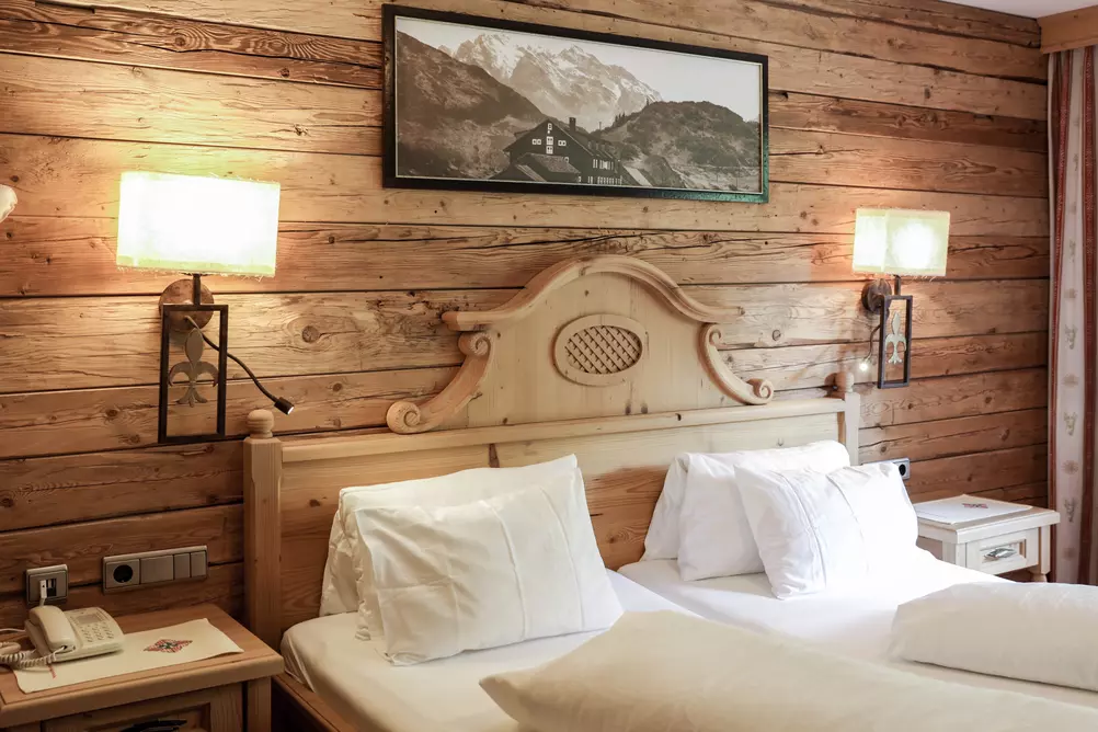 Doppelbett aus Holz in einem Hotelzimmer mit holzvertäfelter Wand