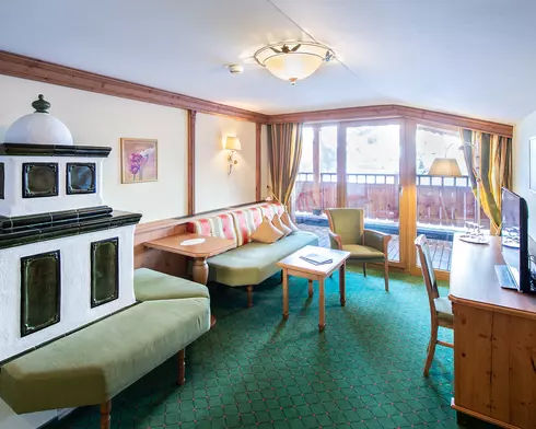 Kachelofen in einem Hotelzimmer mit Balkon, Sitzbank, Schreibtisch und Fernseher