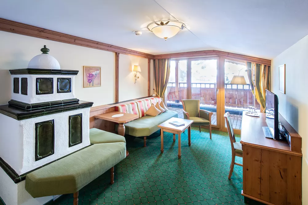 Kachelofen in einem Hotelzimmer mit Balkon, Sitzbank, Schreibtisch und Fernseher