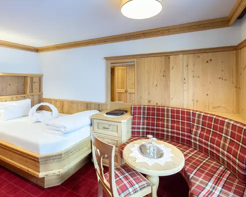Hotelzimmer mit Einzelbett aus Holz und bequemer Sitzbank