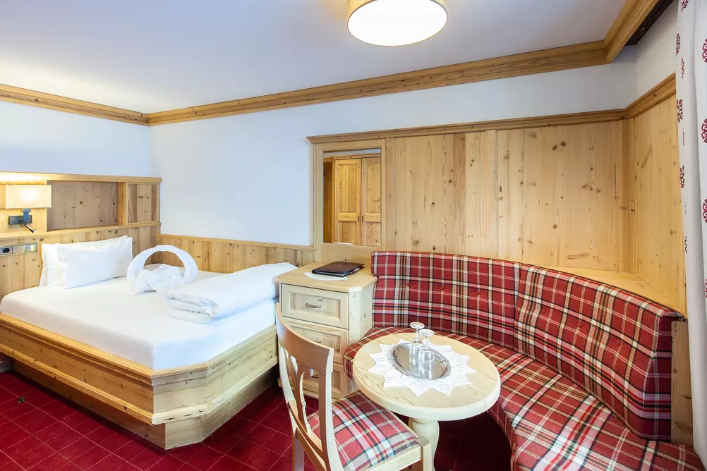 Hotelzimmer mit Einzelbett aus Holz und bequemer Sitzbank