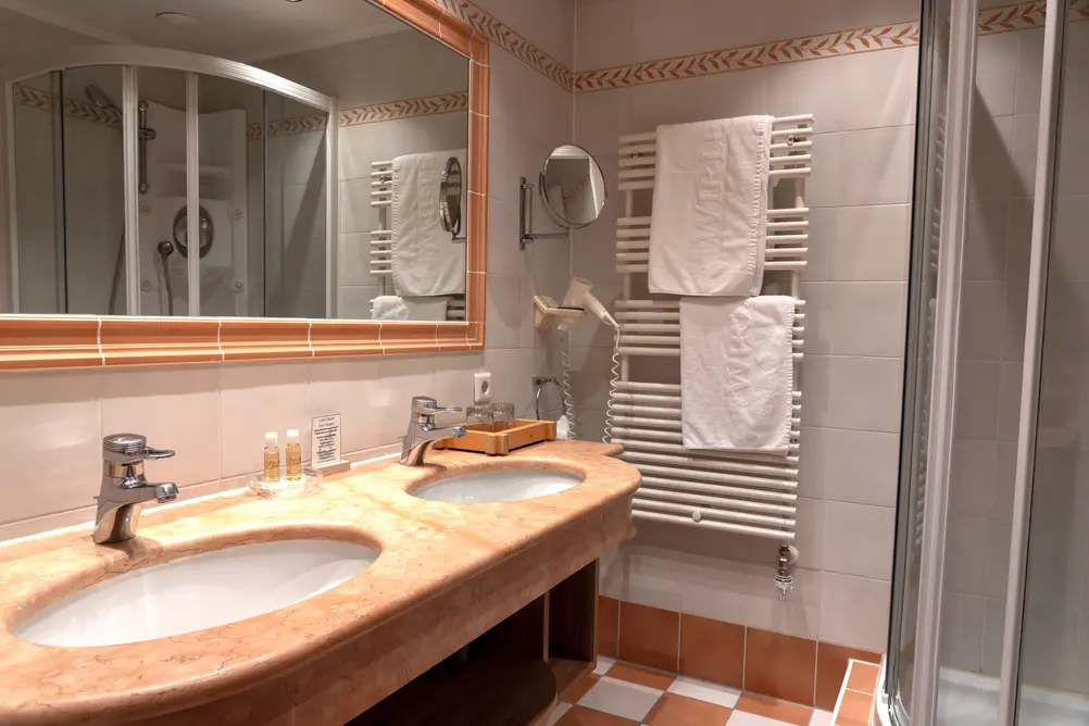 Badezimmer mit zwei Waschbecken, Marmorplatte, großer Spiegelfläche, Handtuchwärmer und Dusche