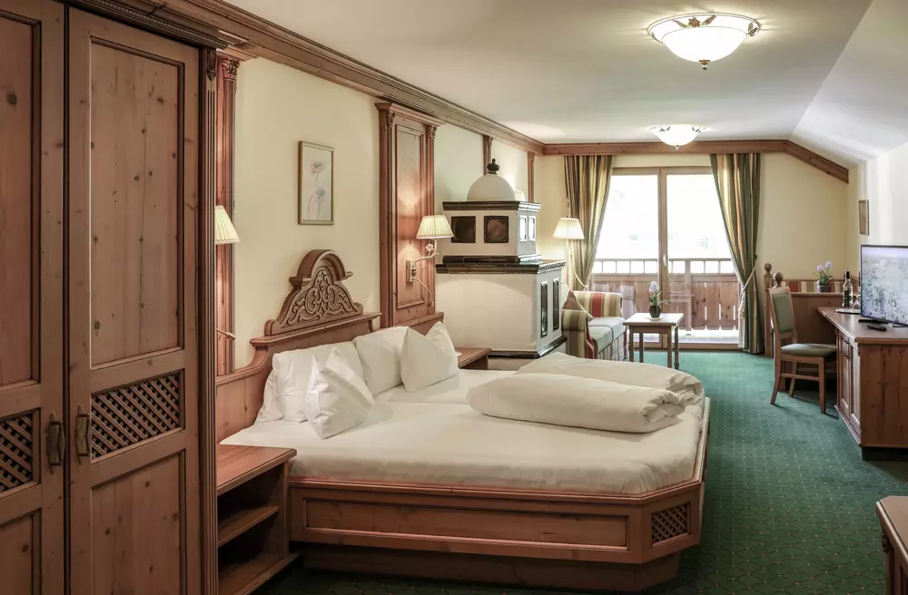 Hotelzimmer mit Doppelbett, Schreibtisch, Kachelofen, Sofa und Balkon